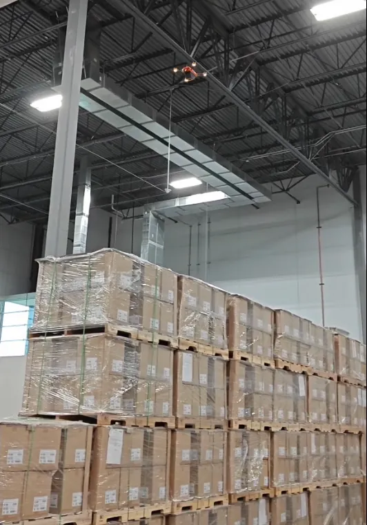 Corvus One autonomous warehouse inventory drone flying near the warehouse roof above rows of floor-stacked pallets, scanning bulk storage with no rack structure