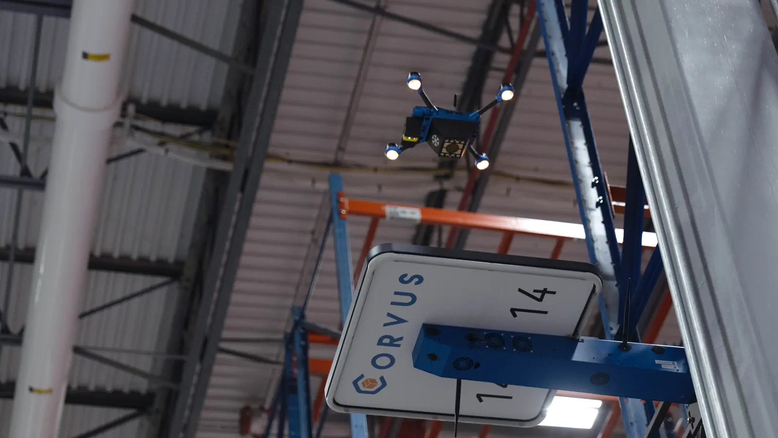 Corvus One for Cold Chain autonomous warehouse inventory drone flying above its Corvus landing pad, mounted to the end of a rack in a cold storage warehouse