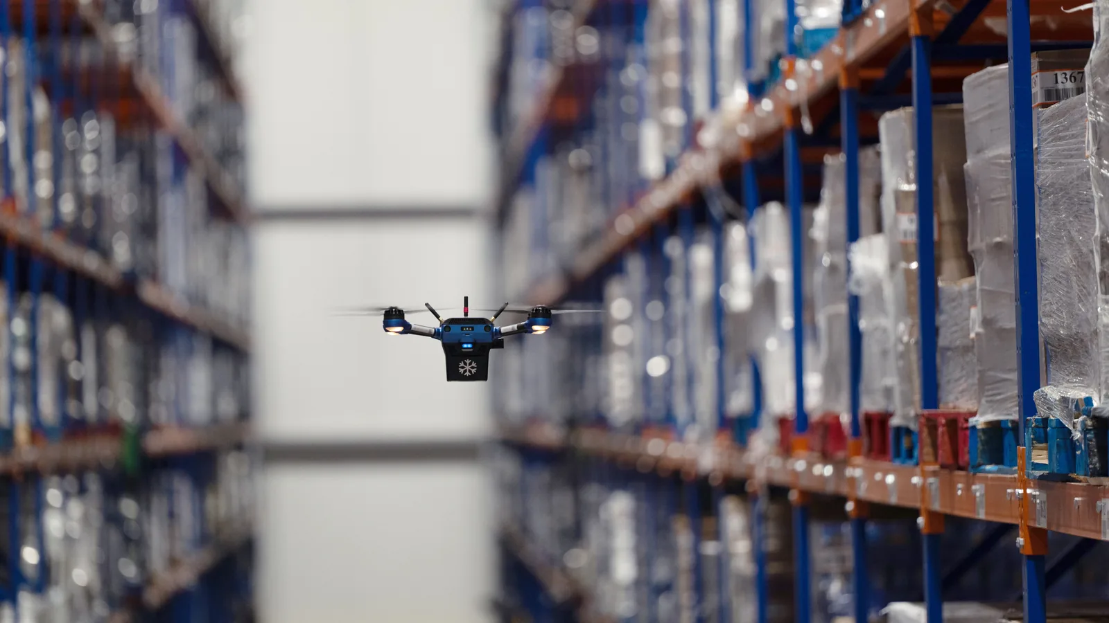 Corvus One for Cold Chain autonomous drone flying an aisle of shrink-wrapped pallets inside a sub-zero cold storage facility