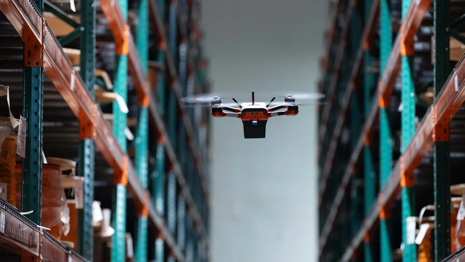 Corvus One autonomous warehouse inventory drone flying down an aisle between tall racks of cable reels