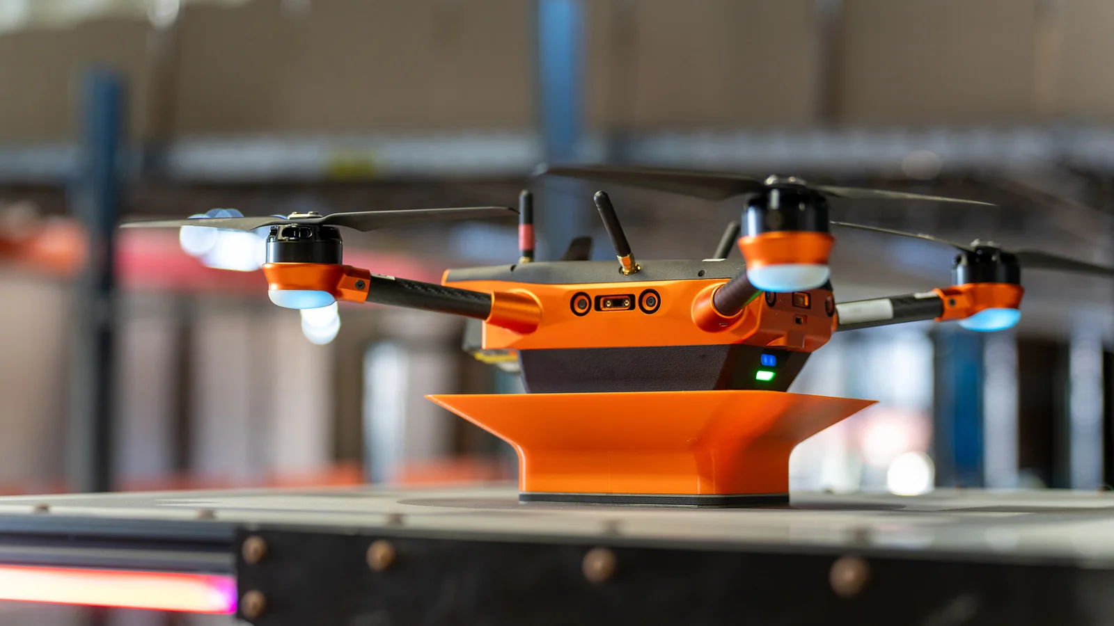Corvus One autonomous inventory drone resting on its landing pad, shown close up with its carbon fiber arms, motors, antennas and sensor ports visible