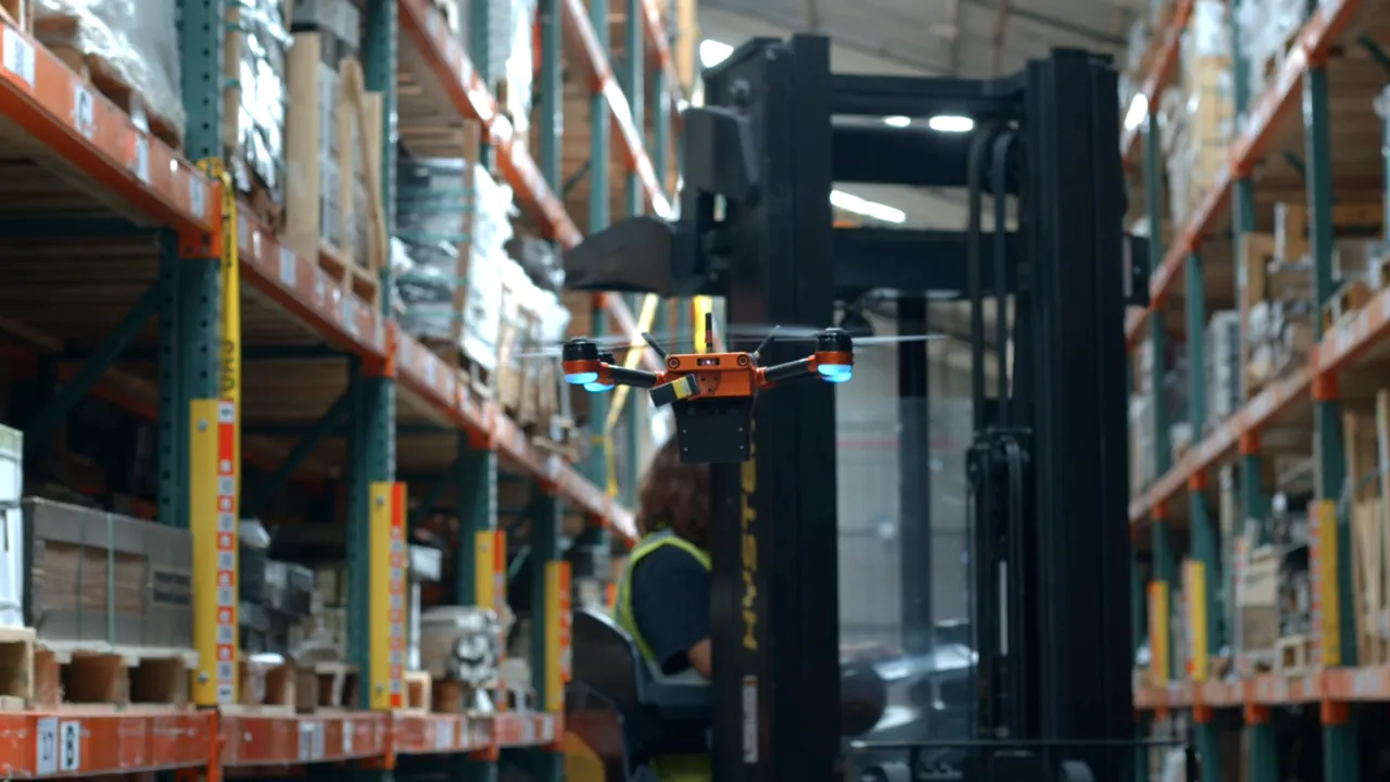 Corvus One autonomous warehouse inventory drone flying in a racked aisle at MSI Surfaces while an operator works from a reach truck directly behind it
