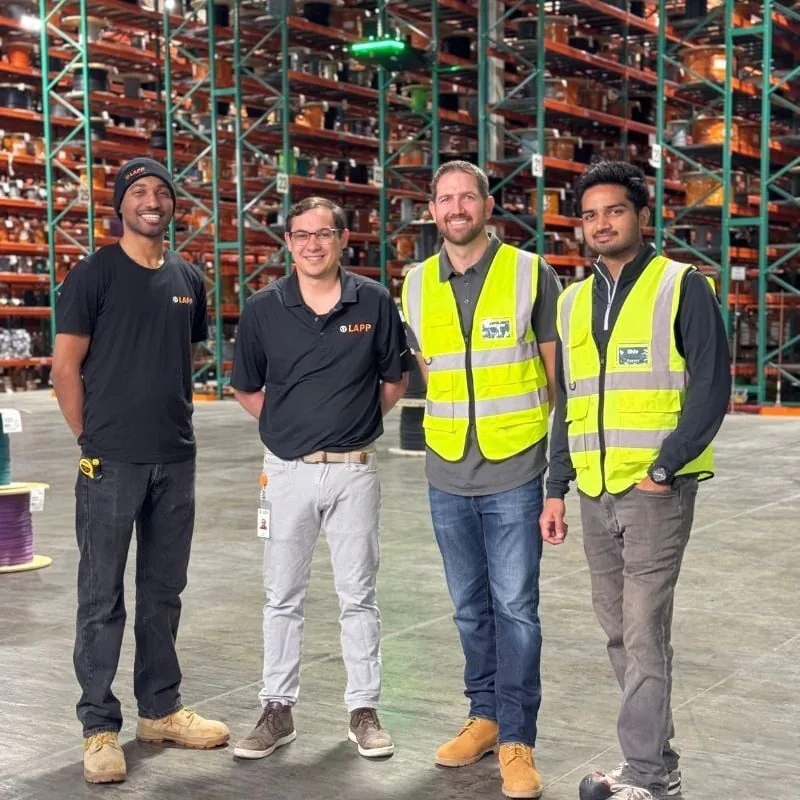 Team members from LAPP USA and Corvus Robotics standing together in front of cable reel racks and the Corvus One landing pad at LAPP's Brownsburg, Indiana distribution center